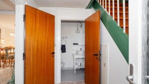 A hallway with wooden doors leading to a bathroom and a staircase with green railings.