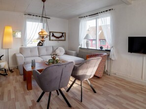 Ein modernes Wohnzimmer mit einer Couch, einem Esstisch, Stühlen, einem Fernseher und einer Heizung.