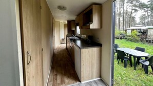 Una cocina moderna con armarios de madera y encimera negra, que da a una zona de comedor al aire libre con mesa y sillas.