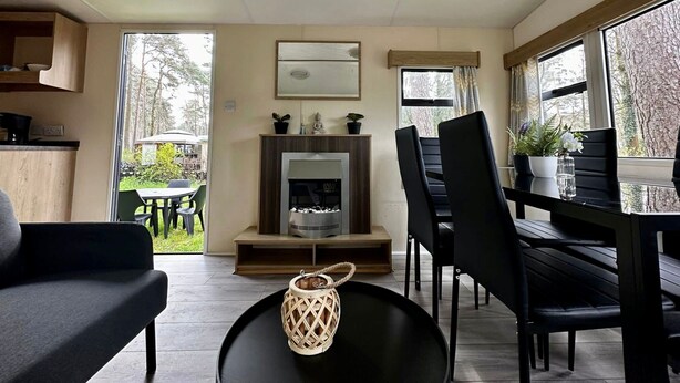 Una sala de estar moderna con chimenea, comedor y ventanas amplias que dan a vistas del exterior.