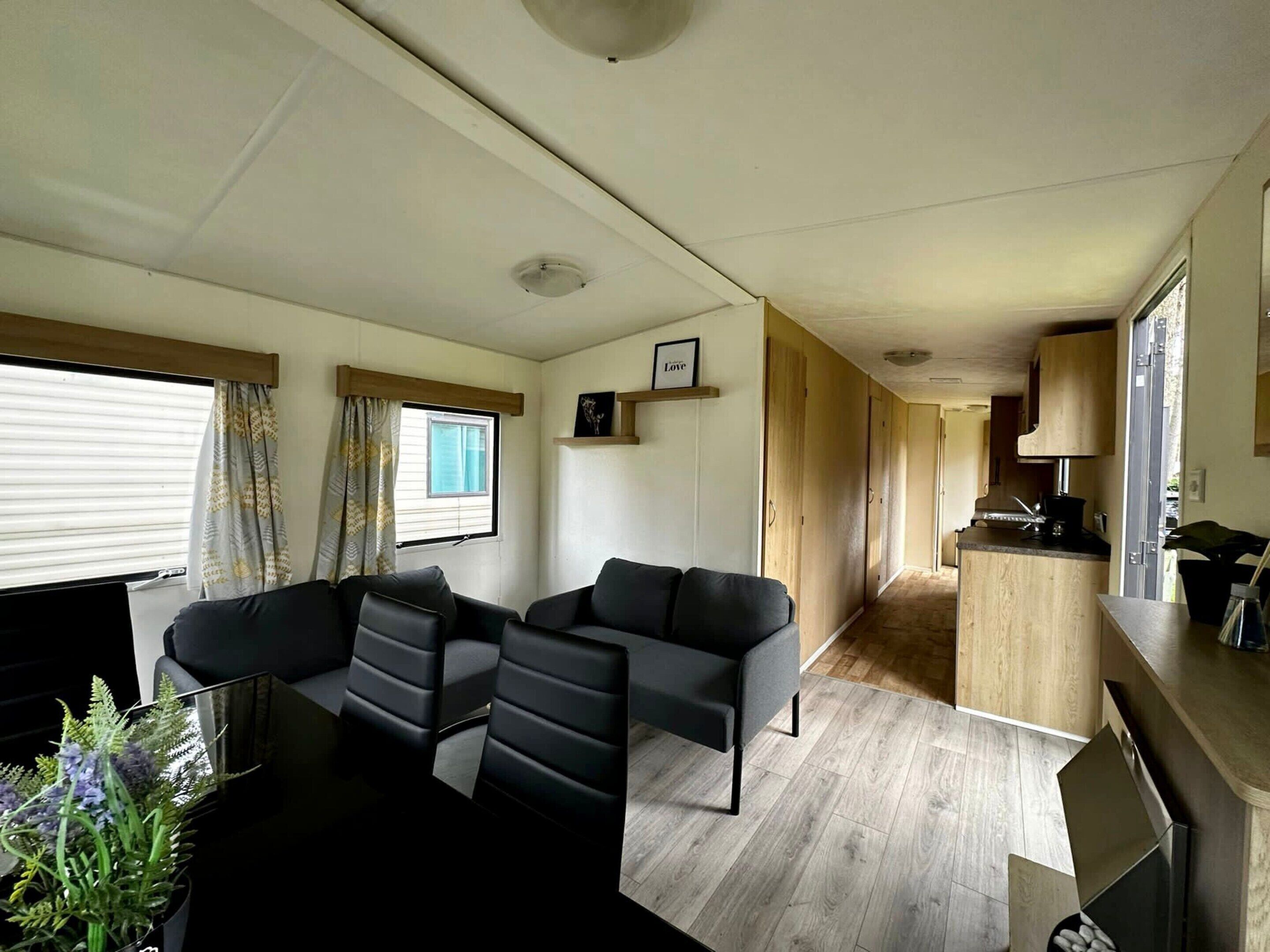 A compact living space with a sofa, a small kitchen area, and a window with curtains.