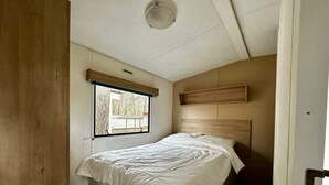 Un dormitorio con una cama, una ventana y un cabecero de madera.