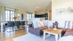 A modern living room with a sofa, coffee table, and dining area. - Lush Villa With Sauna and Fireplace (Dranske)