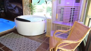 Un bain à remous, un fauteuil en osier et un sauna dans une pièce dont le sol est carrelé et qui possède une fenêtre.
