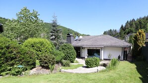 Une maison de plain-pied avec un toit en pente, une véranda et une pelouse bien entretenue.