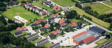 An aerial view of a residential area with multiple houses, a large building with a red roof, and a playground.