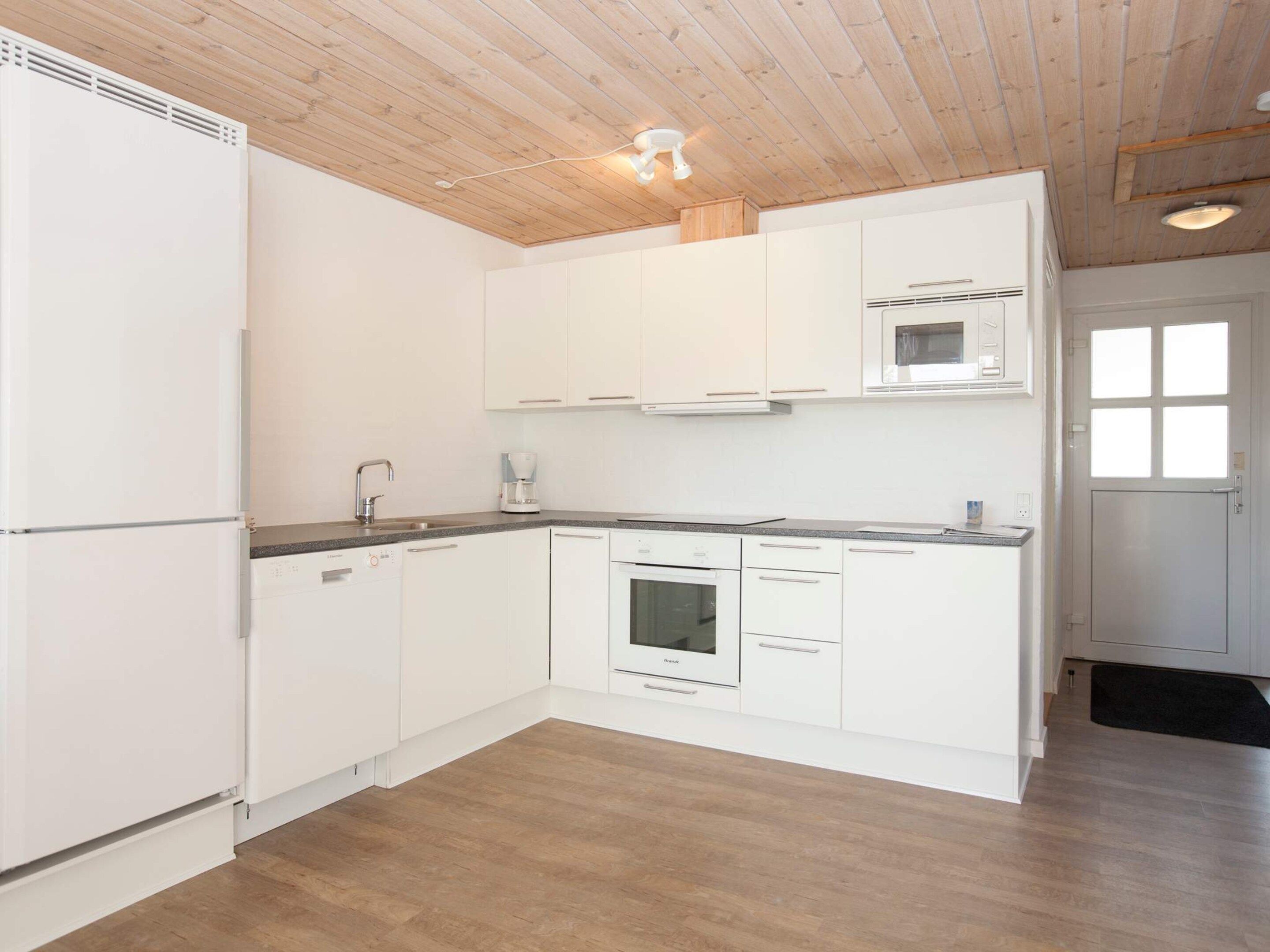 A modern kitchen with white cabinets, a built-in oven, and a microwave.