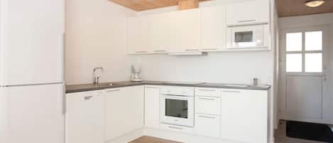 A modern kitchen with white cabinets, a built-in oven, and a microwave.