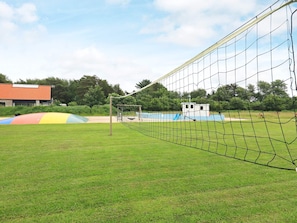 A sports field with a netted goalpost, a small building, and a colorful slide structure. - 6 Person Holiday Park Home in Blavand (Blavand)