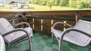A balcony with wicker chairs and a view of a mountain and houses.