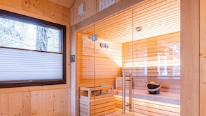 A sauna room with wooden walls, a bench, a stool, and a glass door.