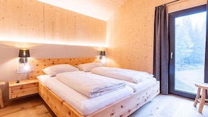 A wooden room with a bed, nightstands, and a window with curtains.