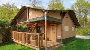A single-story, A-frame structure with a wooden deck, a staircase, and a door.