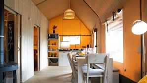A cozy, compact kitchen with wooden flooring, a dining area with a table and chairs, and a large window providing natural light.