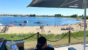 A beach with a wooden deck, lounge chairs, and umbrellas.