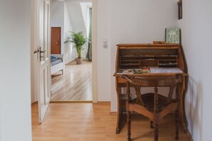 A wooden piano in a hallway with a wooden floor, a door leading to another room, and a potted plant in the background. - Villa G With Pool in Lubbenau (Lübbenau/Spreewald)