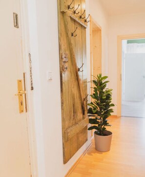 A hallway with a wooden door, a potted plant, and a light switch on the wall. - Villa G With Pool in Lubbenau (Lübbenau/Spreewald)