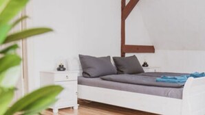 A minimalist bedroom with a bed, bedside tables, and a wooden beam on the wall. - Villa G With Pool in Lubbenau (Lübbenau/Spreewald)