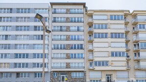 Un immeuble résidentiel à plusieurs étages, doté d’une façade uniforme, de balcons et d’une cour dallée.