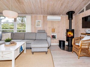 Ein gemütliches Wohnzimmer mit einer Eckcouch, einem Kamin und einem Korbsessel.