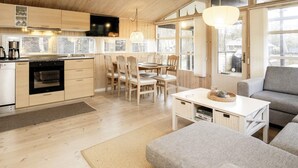 A modern kitchen with wooden cabinets, a dining area with a table and chairs, and a living room with a sofa and a coffee table.