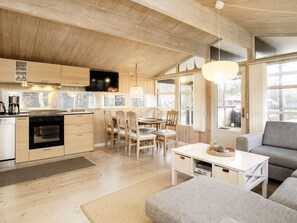 Eine moderne Küche mit Holzausstattung, ein Essbereich mit Tisch und Stühlen sowie ein Wohnzimmer mit Sofa und Couchtisch.