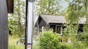 A rustic cabin with a metal water spout and a wooden door.