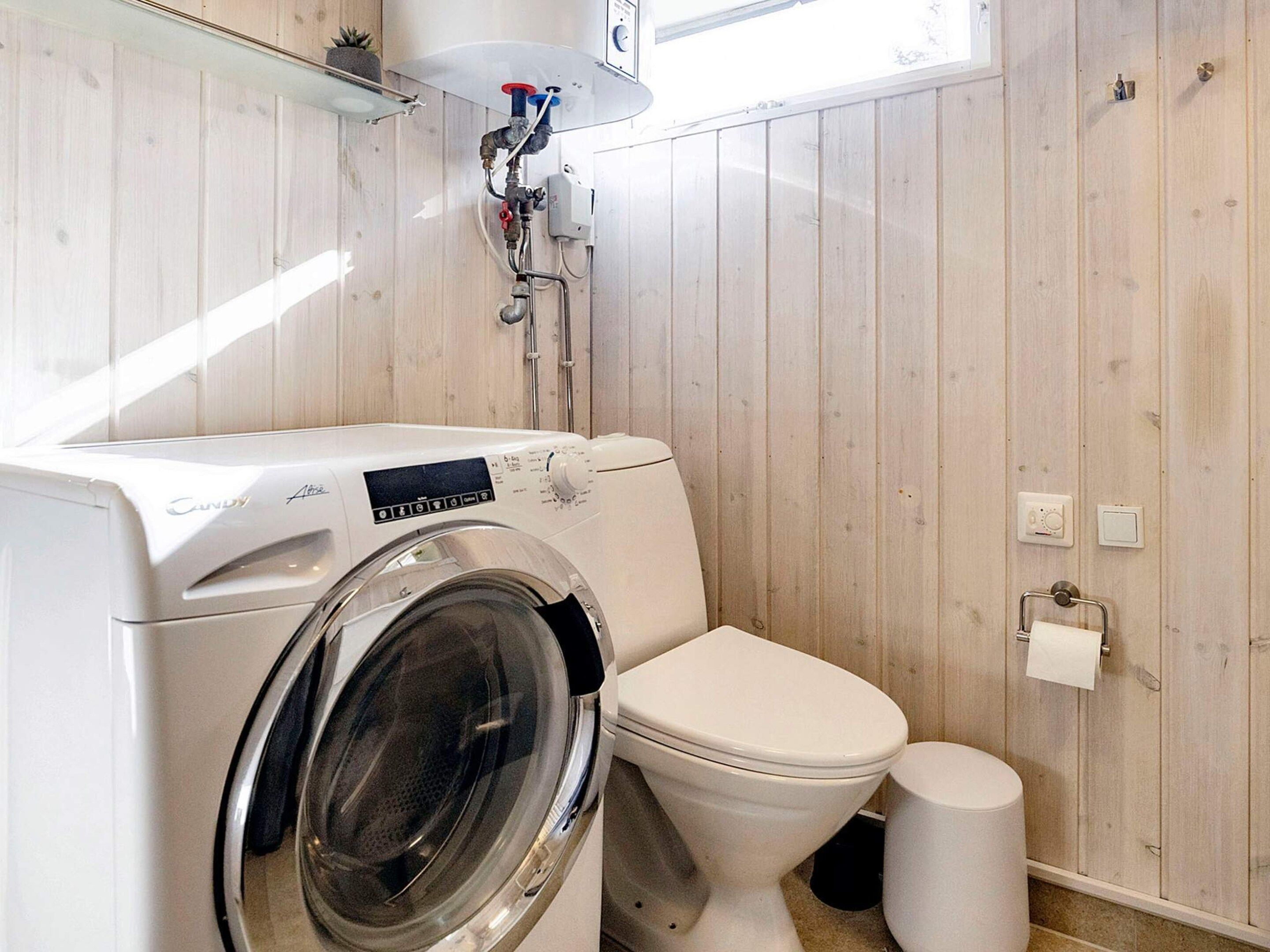 Un bagno funzionale con lavatrice, WC e una piccola finestra.