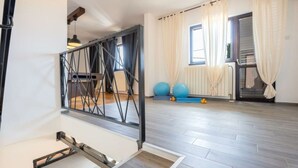 Une pièce spacieuse avec un plancher en bois, un escalier doté d’une rampe en métal et une fenêtre avec des rideaux.