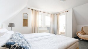 A hotel room with a large bed, two bedside tables, a chair, a lamp, and a window with curtains. - on the Sunny Slope Modern Retreat (Eslohe)