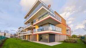 Een modern appartementencomplex met balkons, grote ramen en een verzorgd gazon.