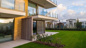 Een modern meerlaags gebouw met grote glasramen, een plat dak en een verzorgd gazon.