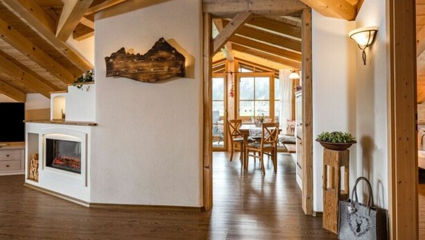 A spacious room with a wooden ceiling, a fireplace, a dining area with chairs and a table, and a wooden bench. - Konigssee - Reich Family (Schoenau am Koenigssee)
