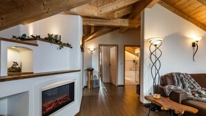 A cozy living room with a fireplace, wooden beams, a sofa, and a bench. - Konigssee - Reich Family (Schoenau am Koenigssee)