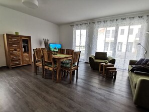A living room with a wooden dining table, chairs, a sofa, and a television. - Holiday Apartment Lotte Een (Zingst)