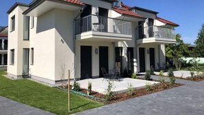 A modern two-story residential building with balconies, a paved driveway, and a well-maintained lawn. - Holiday Apartment Lotte Een (Zingst)