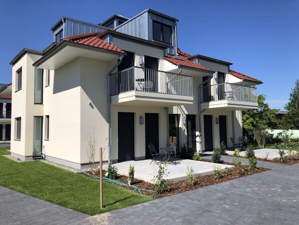 A modern two-story residential building with balconies, a paved driveway, and a well-maintained lawn. - Holiday Apartment Lotte Een (Zingst)
