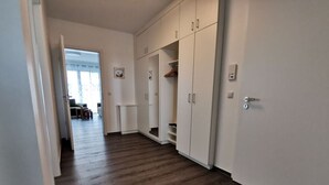 A hallway with wooden flooring, white walls, and a wardrobe with multiple doors. - Holiday Apartment Lotte Een (Zingst)