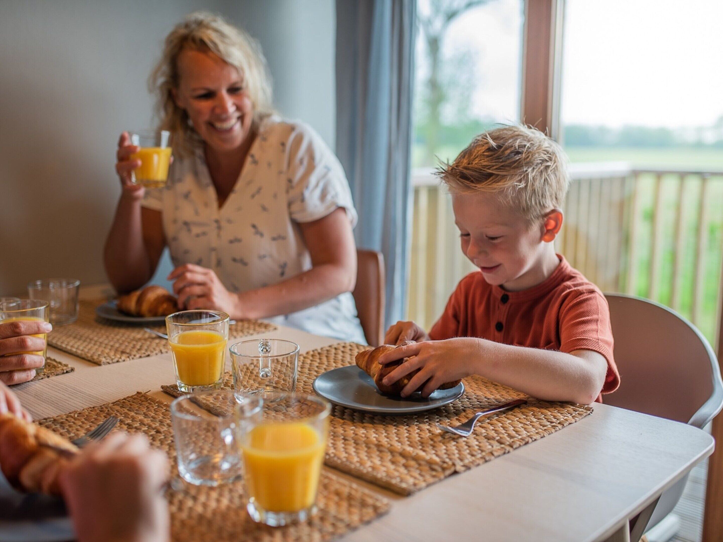 A breakfast setting with a table, plates, glasses, and a window view.