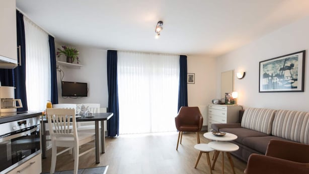 A modern living room with a sofa, coffee table, and dining area. - Holiday Home Villa Piep (Nebel)