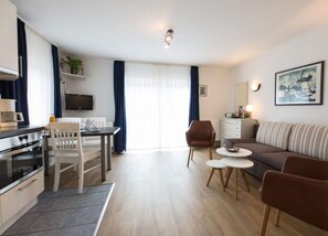 A modern living room with a sofa, coffee table, and dining area. - Holiday Home Villa Piep (Nebel)