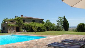 Edifici de pedra amb piscina i gandules.