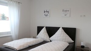 Un lit avec une tête de lit noire, deux oreillers et une table de chevet avec une lampe.