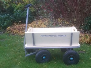 A wheeled cart labeled "FEWO NEPTUN 211 VITAMAR" in a garden setting.