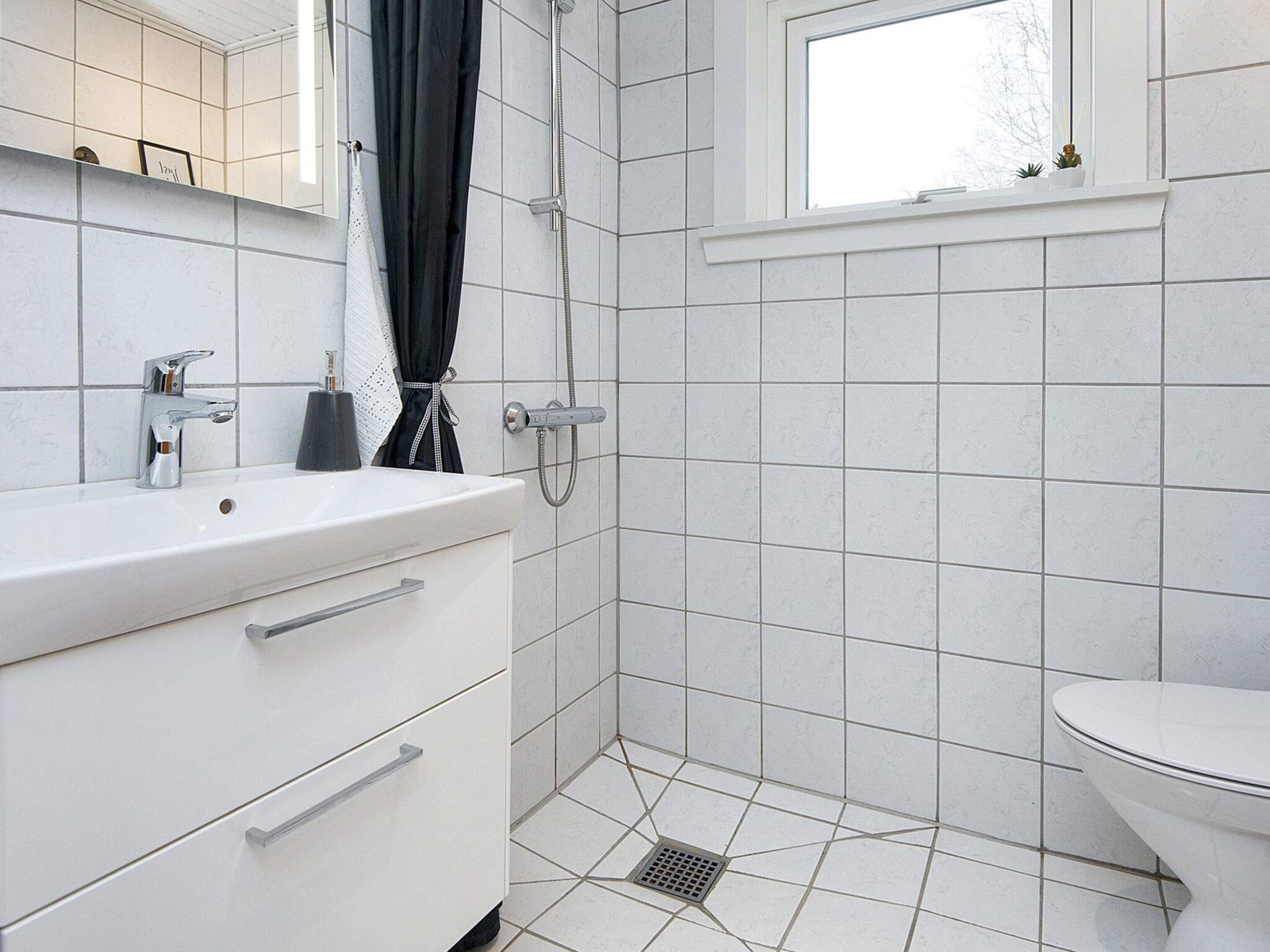 Un baño con lavamanos blanco, inodoro y zona de ducha.