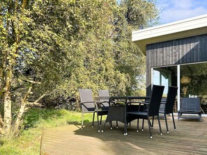 An outdoor deck with a table and chairs, surrounded by trees. - 4 Star Holiday Home in Fano (Fano)