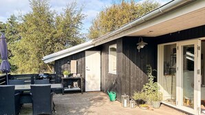 Un bâtiment en bois doté d’un patio, de mobilier d’extérieur et d’une porte-fenêtre coulissante.