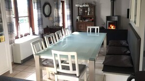 A dining area with a long table and chairs, a fireplace, and a sofa. - Fischerhaus by the sea (Bredene)
