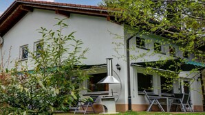 A two-story house with a patio area, a chimney, and a large rock in the foreground. - Holiday Home Black Forest (Feldberg)