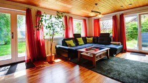 A cozy living room with a wooden ceiling, a blue sofa with cushions, a coffee table, and a potted plant. - Holiday Home Black Forest (Feldberg)